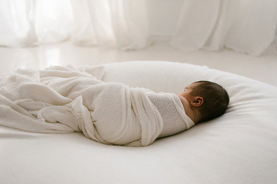 Newborn baby laying on a cream blanket in Laurie Baker's white studio in Homer Glen, Illinois