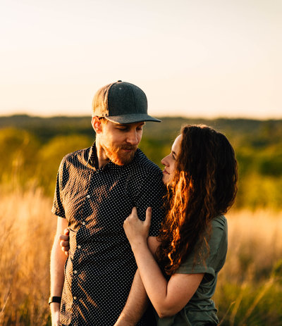 husband wrapping arms around wife at sunset