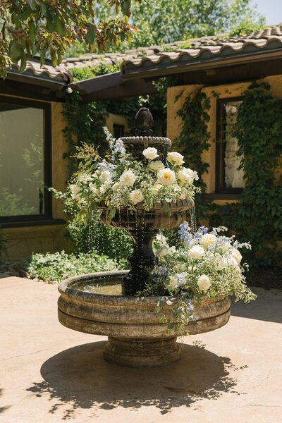 Garden fountain covered in lush florals at Villa Parker — European-inspired Colorado wedding venue detail.