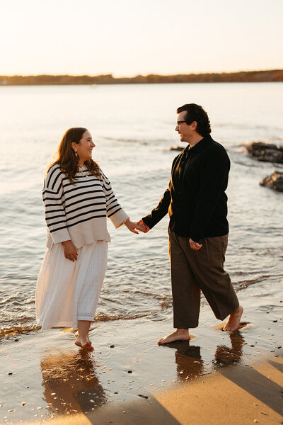 A couple walks on Kettle Cove beach in Cape Elizabeth, Maine Photographed by Hattie Mae Photography