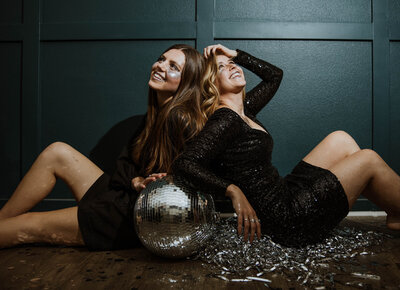 women leaning against each other with disco ball