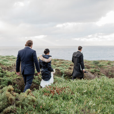Couple walking out to their sea side Big Sur cliff elopement location with officiant