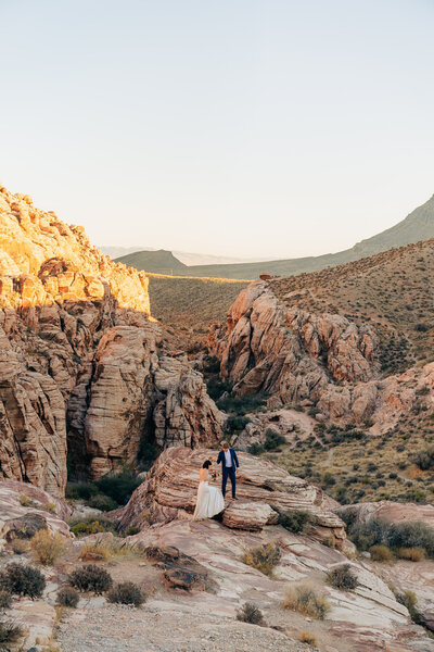wedding couple climbs rocks in desert