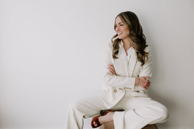 Website copywriter Erika Fitzgerald wearing a white suit in a studio portrait, representing her modern, strategic website copywriting process 