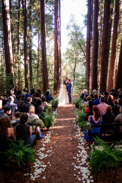 Bride and groom are standing in the forest exchanging wedding vows at Sequoia Retreat Center in Santa Cruz.