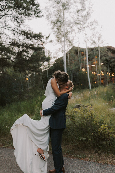 Groom carrying his bride while kissing each other