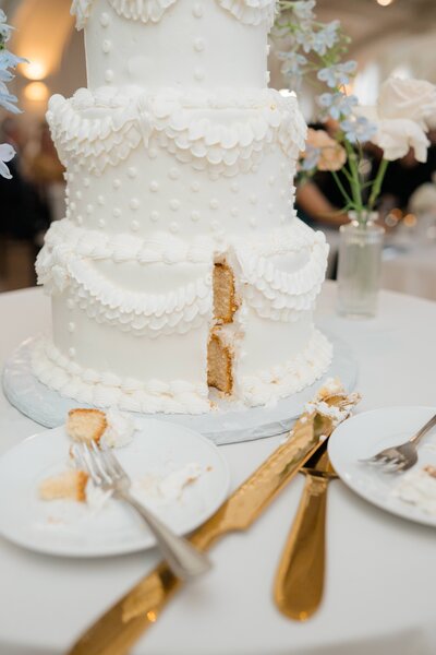 An antique art deco style wedding cake after the bride and groom cut the cake at The Cottonwood Hotel, a weddng venue in Omaha NE. Photo by Anna Brace, a Nebraska wedding photographer.