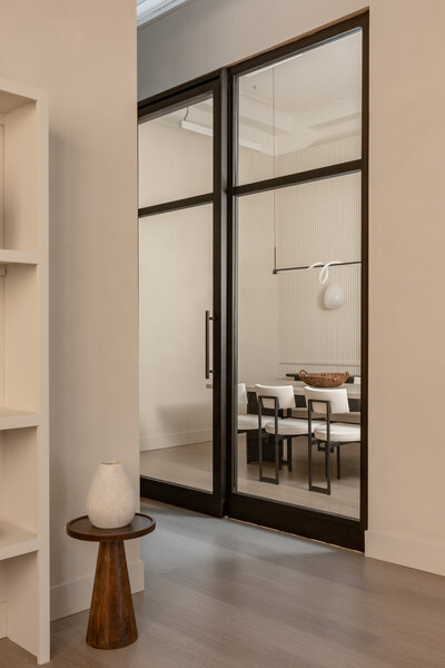 dining room table with 3 chairs with a styled bookshelf with decor pieces behind