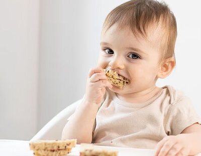 baby eating food in high chair 