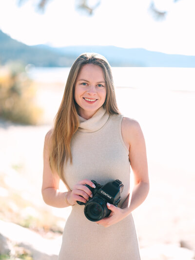 Anastasiya Martynova lead photographer at Anastasiya Photography holding contax 645 film camera while wearing a cream turtleneck sleeveless dress in front, lake tahoe photographers