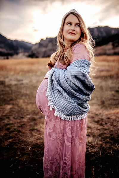 pregnant mother cradling belly during photo session in Boulder by Courtney McQueeney