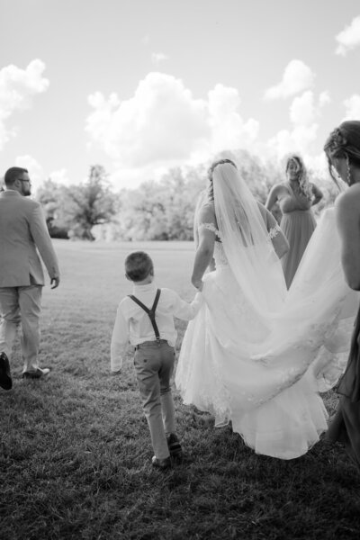 Bride and groom in Saint Louis, Missouri kissing and dipping on a green grass hill. She is holding a bouquet and has a veil.