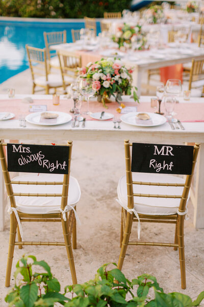 Wedding reception table setup by a pool with Mr and Mrs Right signs on gold Chiavari chairs.