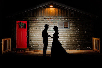 Bride in white dress and groom in marine corps uniform pose for a photo by Scranton Wedding Photographer Eric Boylan in front of a red stucco building at Nay Aug Park in Scranton, Pa