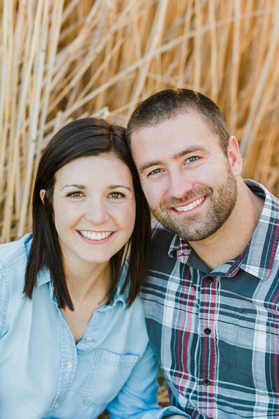 Husband and wife smiling together in a field.