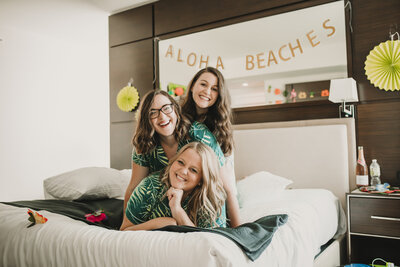 three women sitting on bed laughing