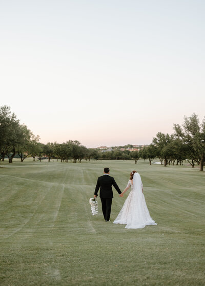 bride and groom walking away on a golf course