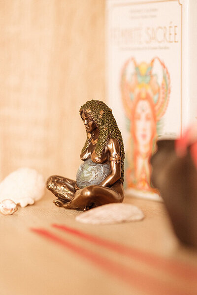 Statue en de femme enceinte nue en tailleur. Arrière plan oracle de carte sur la féminité sacrée.
