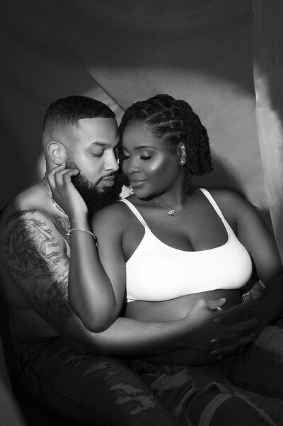 A pregnant couple laughs in maternity photos in the Enid A. Haupt gardens