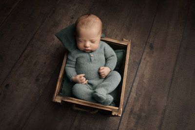 A sleeping newborn posed in a rustic bucket by a New Orleans Family, Maternity & Newborn Photographer.