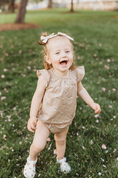 toddler girl smiling with two beige hair bows 