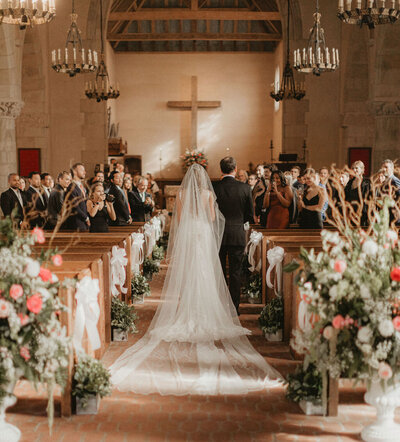 a bride and her father walking down the aisle in a church