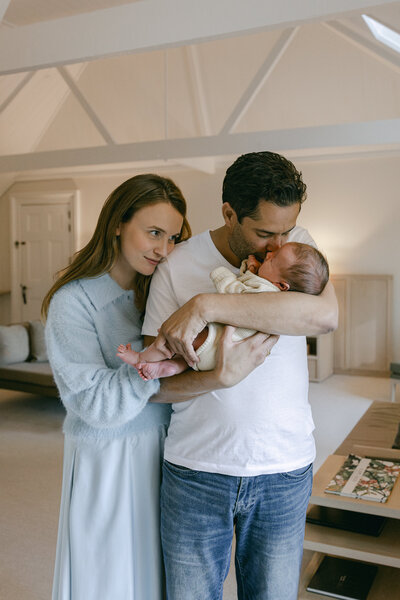 A family photo of mum and dad snuggling into each other with their newborn baby