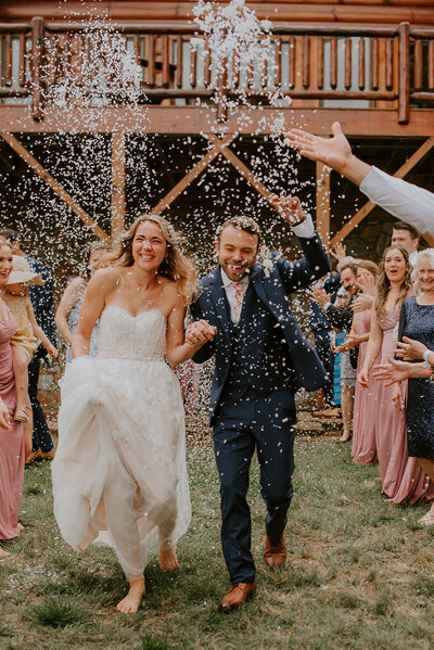 Bride and groom running through confetti toss