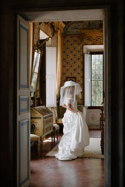 A person in a wedding dress with a large hat and veil on. 