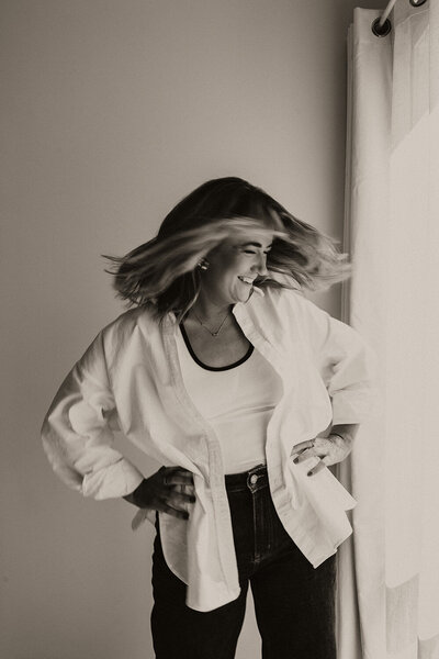 Black and white branding portrait by Sunshine Coast photographer, capturing a confident woman mid-spin in natural window light.
