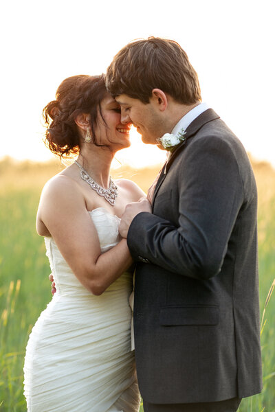 bride and groom kiss at golden hour in field at NC wedding