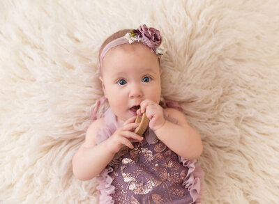 Brooklyn, NY Photographer captures twin baby boy and girl for baby milestone portrait. Babies are sitting beside each other on an infant daybed. Baby girl is in a white organza ruffled onesie and baby boy is in a taupe knit romper and bonnet.