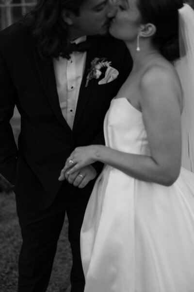 An Austin wedding photographer captures a beautiful black and white image of a bride and groom sharing a romantic kiss.