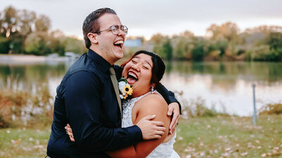 bride and groom laughing with the lake in the background