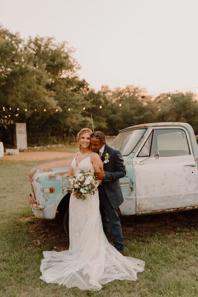 bride and groom posing by vintage truck