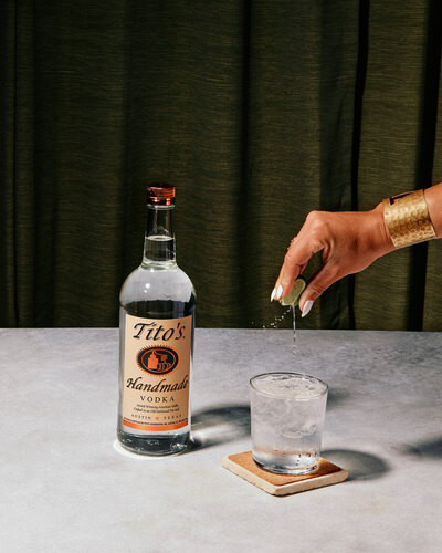 A clean and crisp image of Tito’s Handmade Vodka being poured into a glass over ice. Captured by Mica McCook, this photograph highlights the clarity of the vodka and the refreshing simplicity of the cocktail preparation.