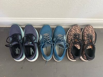 three pairs of blue, gray, black and brown animal print running sneakers. they are on a dark gray floor