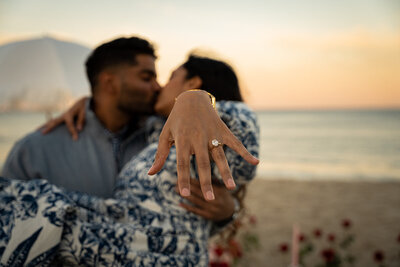 couple share a kiss showing an engagement ring