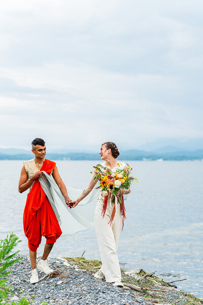 couple holding hands walking alongside lake champlain
