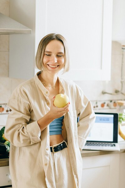 Smiling woman holding an apple representing healthy lifestyle and medically assisted weight loss at Wellness and Hormone Health in Centennial, CO