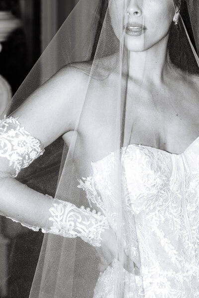 Black and white photo of bride's veil over her face and lacy dress