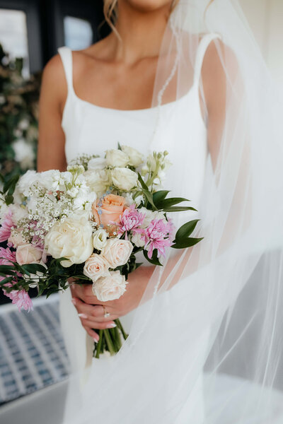 Close-up of a bride holding a romantic pastel wedding bouquet, captured by a Michigan and Ohio wedding photographer for couples seeking timeless floral inspiration.