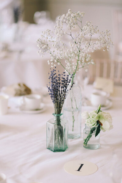 Lavender and baby's breath in glass bottles as table decor