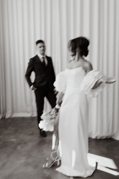 blurry photo of bride looking back at groom behind her