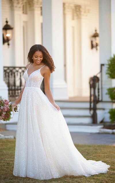 SPARKLING A-LINE WEDDING DRESS WITH BEADED TULLE Shine on, bridal beauty! This sparkling A-Line wedding dress from Martina Liana is here to light the way to style perfection. The entire gown features an artful mix of sequined and beaded tulle for a rich texture and dazzling radiance. The soft V-neckline and shoestring straps keep the look feeling light and effortless, while the slightly sheer bodice offers a semi-nude look which really enhances the embellishments of the gown. The full skirt is lush and full of movement, while the open V-back adds the perfect touch of simplicity to this ornate style.
