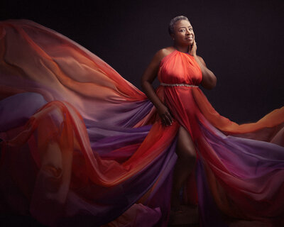 Woman in her 50s in a flowing brightly coloured dress. Taken in studio by Norwich Photographer Claire Howes.