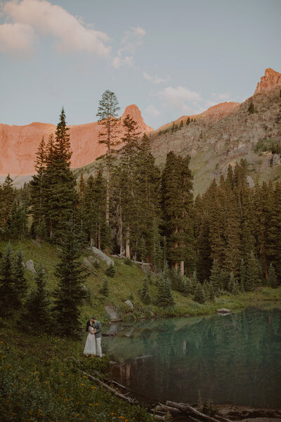 Couple stands on the edge of an alpine lake in Colorado