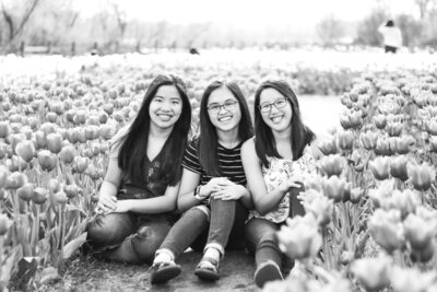 three girls sitting in a field of tulips smiling