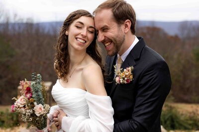 bride and groom laughing together with mountains in the background