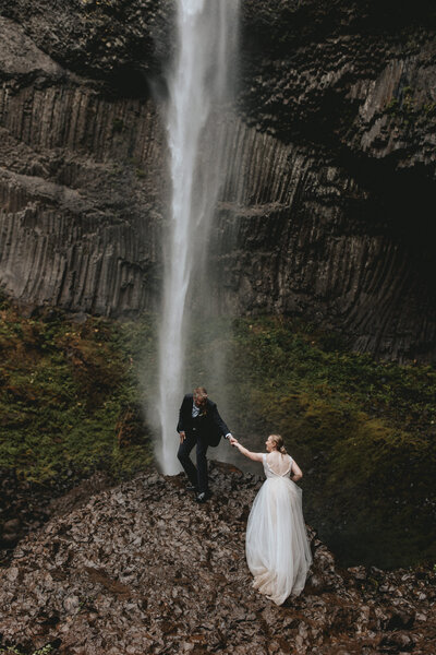bride and groom holding hands in mountains
